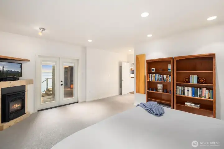 Serene primary suite with fireplace and deck access, creating a peaceful sanctuary above the shoreline.