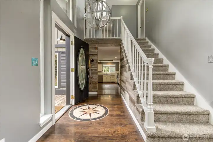 Bright and inviting 2-story entry featuring unique flooring details and a soaring ceiling that fills the home with natural light