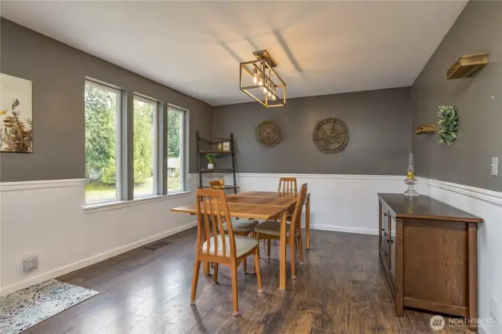 The bright dining room features classic wainscoting and modern floating shelves, creating a perfect space for both casual meals and formal entertaining