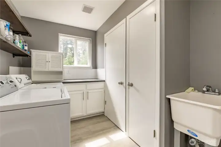 Convenient laundry and mudroom located between the garage and kitchen, featuring a utility sink and two large closets for excellent organization