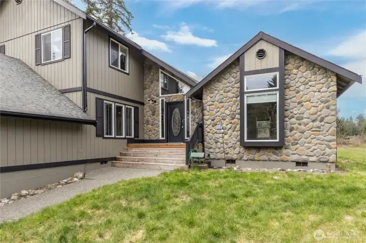 The main entry features beautiful decorative stonework and wide, welcoming steps