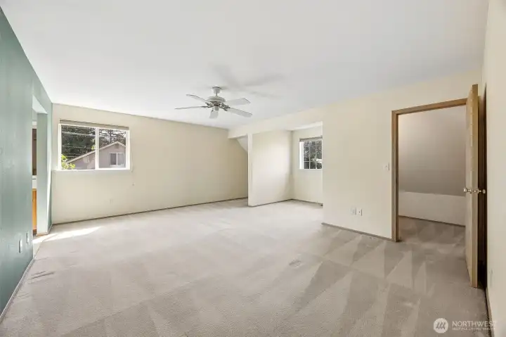 Generously sized primary suite features dual walk-in closets, a ceiling fan for year-round comfort, and a private ensuite bath for a relaxing retreat.