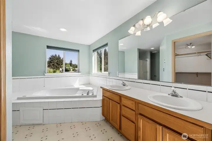 Primary bathroom with oversized jetted tub, walk-in shower, double sink vanity + large walk in closet.
