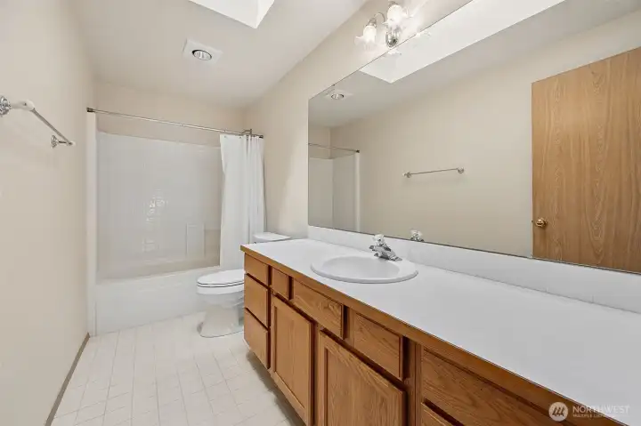 Main hall bathroom upstairs with skylight, large vanity & tub/shower combo.