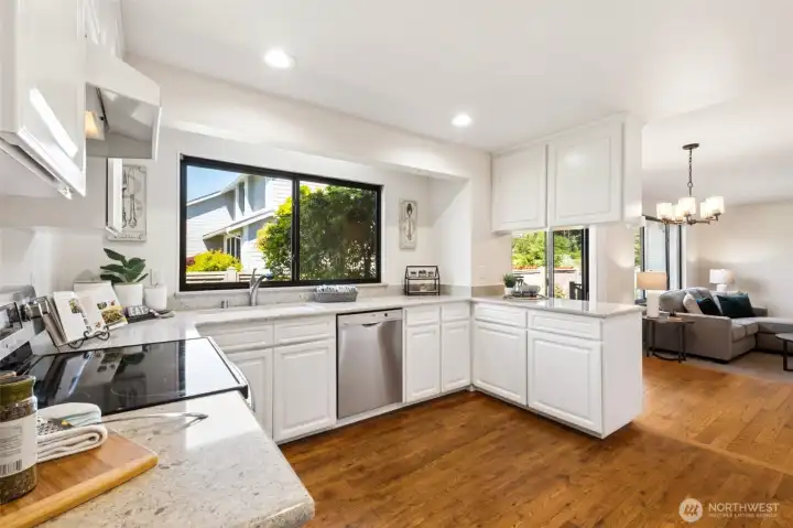 The bright and inviting kitchen offers abundant cabinetry, generous counter space, updated finishes, and seamless flow to the adjoining living and dining areas