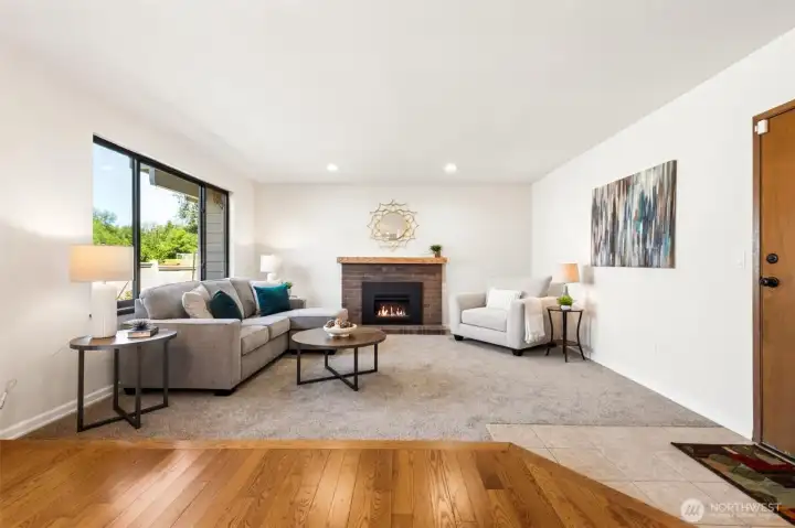 Spacious family room featuring a cozy gas fireplace, plush carpeting, and a large picture window that fills the space with natural light