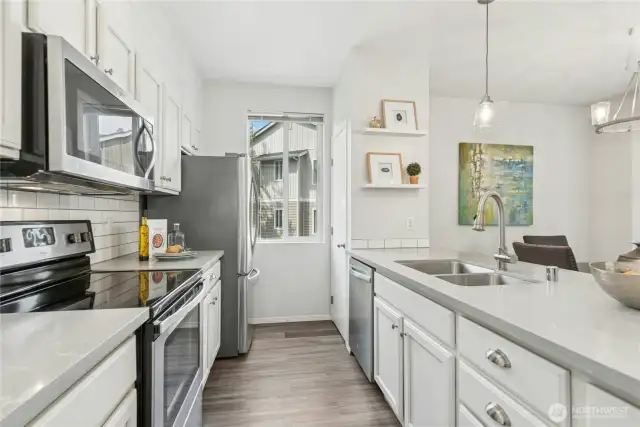 Stainless steel appliances and pantry by window.