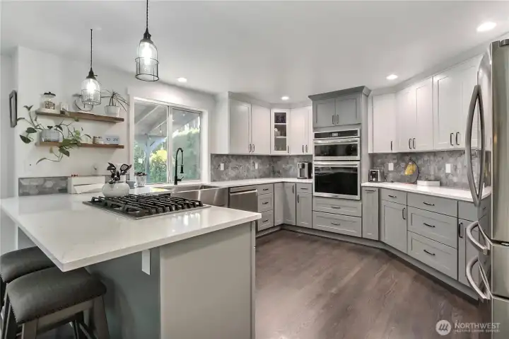 This photo offers a different perspective, highlighting the well-lit and spotless kitchen, specifically emphasizing the window that provides inviting views of the outdoor deck area.