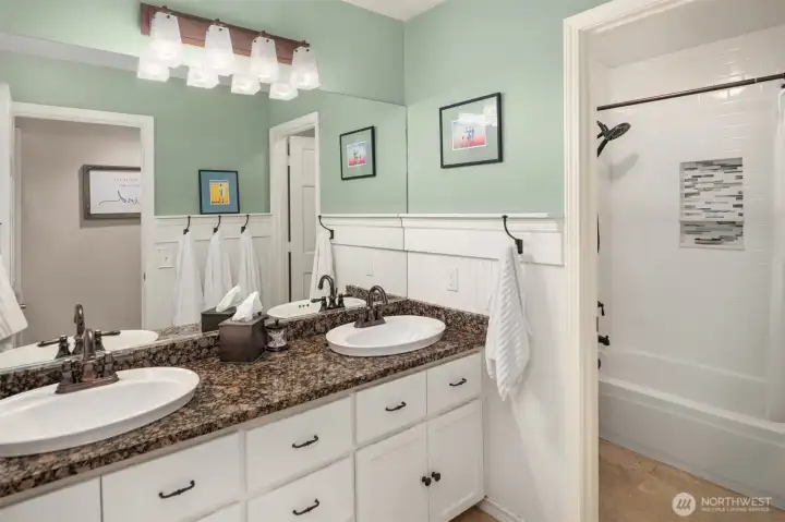 Guest bathroom with beadboard walls and subway tile shower with built-in nook.