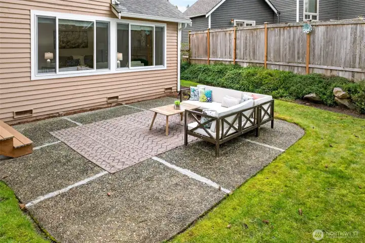 The backyard patio extends the living space outdoors and creates a comfortable area for dining, relaxing, or entertaining. Fenced and framed by mature landscaping, the setting feels private, usable, and easy to enjoy.