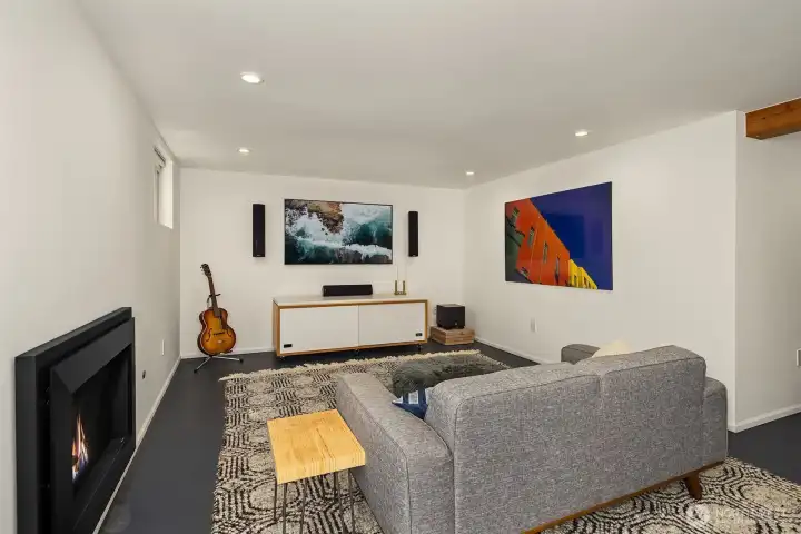 Large lower level media room with gas fireplace.