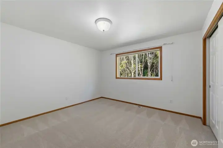 Comfortable third guest bedroom with peaceful views of the private side yard.