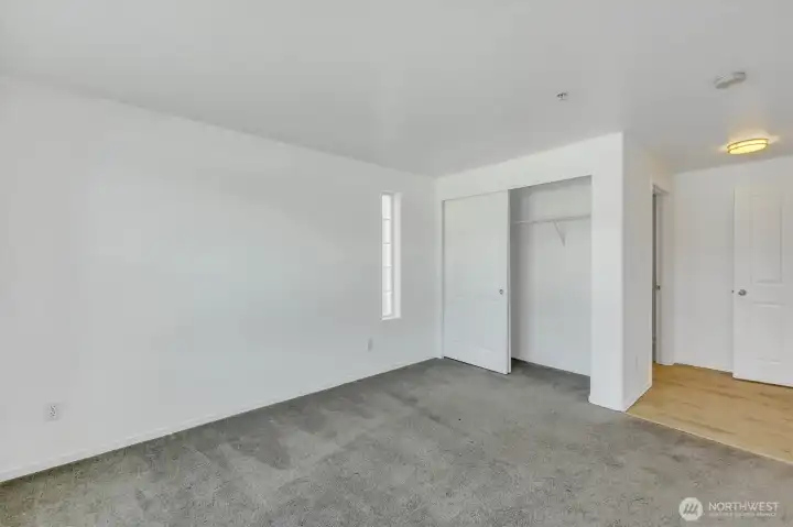 Primary bedroom. Ensuite bathroom is behind the closet. To the right is the entry from the hallway.