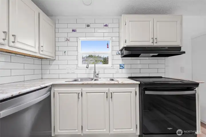 Tiled back splash in this light and airy kitchen which looks out over the yard and garden. Complete with new dish washer and induction/air fry range