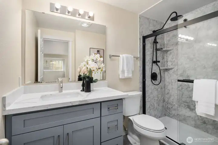 Beautifully updated second full bathroom featuring a stylish gray vanity, elegant tilework, and a sleek glass enclosed shower. Beautifully updated second full bathroom featuring a stylish gray vanity, elegant tilework, and a sleek glass enclosed shower.