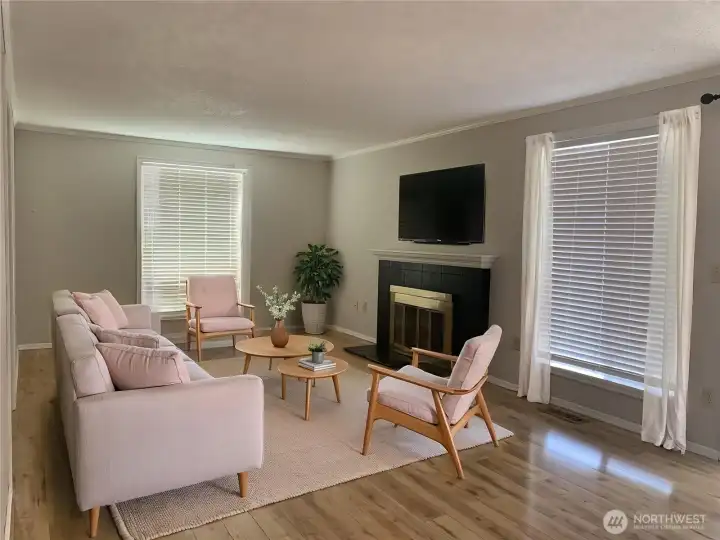 The home features a large living room with wood flooring that opens to the dining room and has access to a fenced yard. The home features a large living room with wood flooring that opens to the dining room and has access to a fenced yard.