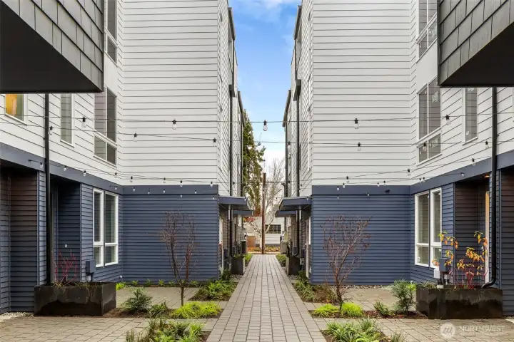 This charming courtyard connects the homes, offering a peaceful, landscaped walkway illuminated by overhead string lights—a welcoming touch to this vibrant community.