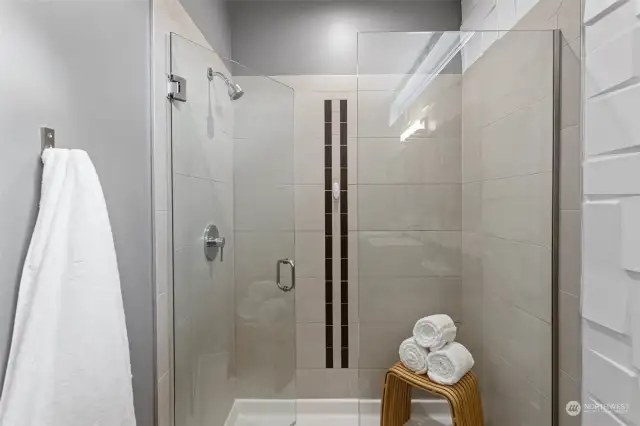 Primary en-suite with large walk-in tiled shower, double vanity with vessel sinks, custom wood trimmed mirrors, tiled flooring and 3D wall paneling.