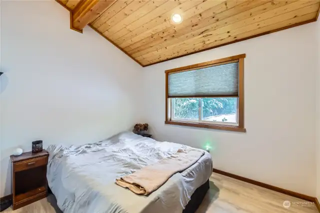 This large second bedroom features a vaulted ceiling, creating an open and inviting atmosphere with plenty of space to relax. (shown with king bed)