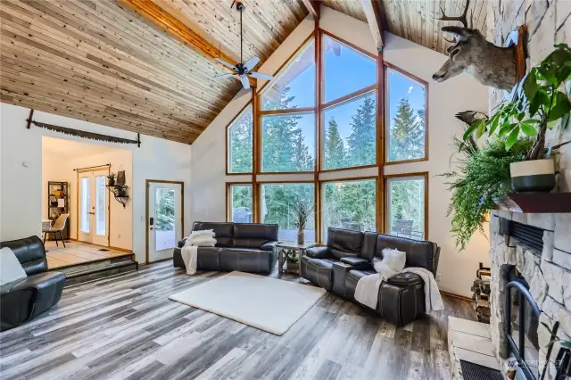 The living room’s breathtaking wall of windows brings the outdoors in, filling the space with natural light and offering stunning views of the surrounding landscape in every season.