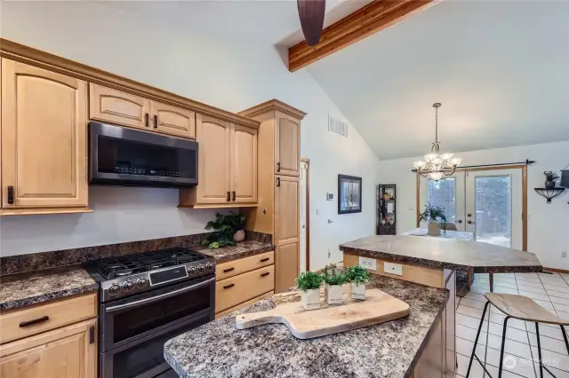 The spacious kitchen features a large island with storage, a double walk-in pantry, and French doors with built-in blinds that open to the deck for seamless indoor-outdoor dining.