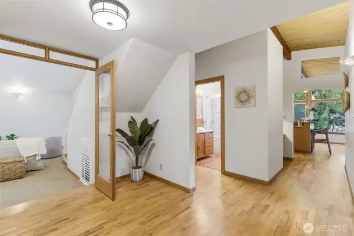 This hallway with natural wood floors gives access to bedrooms, family room and main bath.