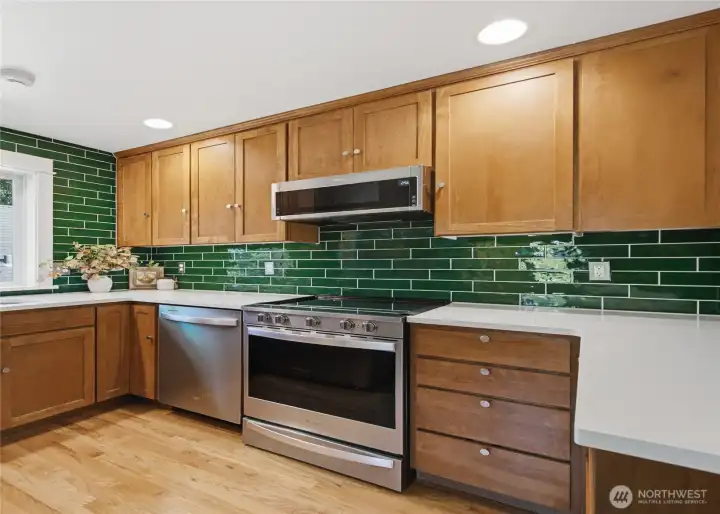 Elegant quartz countertops paired with a custom, ceiling-height wraparound ceramic green undulating tile backsplash.
