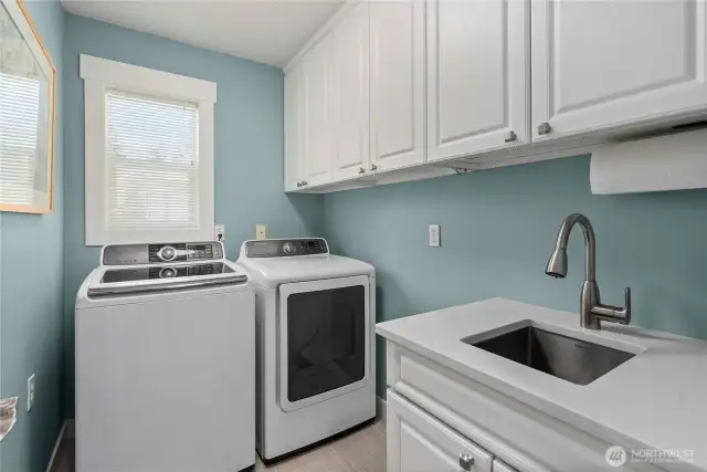 Laundry room includes a handy utility sink and ample storage space