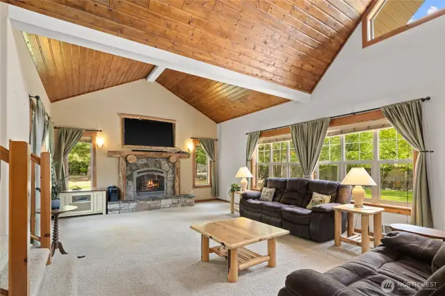 Living room with vaulted ceilings, fireplace, natural light.