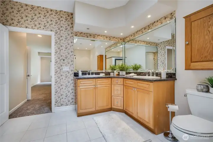 The dual-sink vanity offers plenty of countertop space and storage room below. The primary suite bathroom also features a step-in tub and a linen closet.