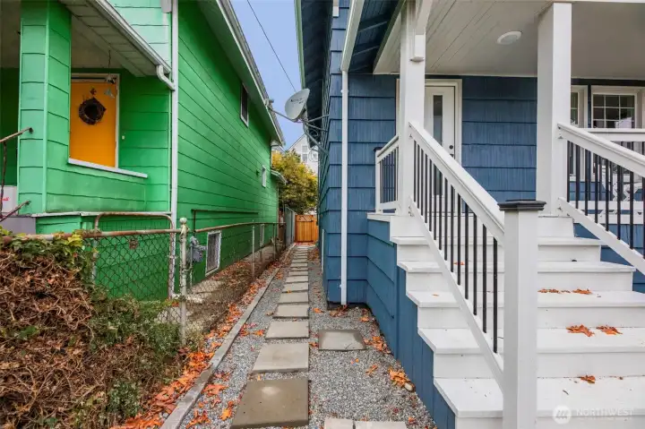 Walkway on the side of the home leads to the back door for the home, private entrance for the basement, and to the units that will be behind the fence.