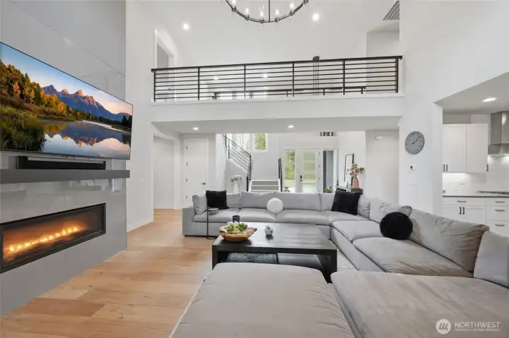 Living room is open yet cozy with gas fireplace and warm engineered wood floors.