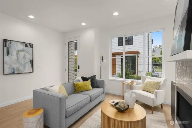 This cozy living room corner is perfect for reading or relaxing. The large windows provide a view of the lush outdoor greenery, adding to the room's tranquility.