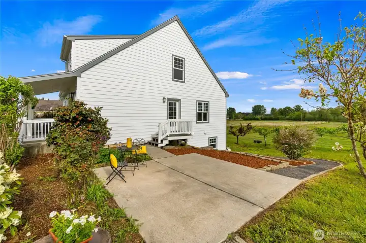 Side view of the home with a Trex deck & patio between the house and the barn. A gravel pathway leads to the lower level of the home & terraced garden beds along the path provide great gardening opportunities!
