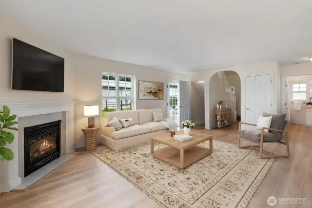 Virtually staged living room with natural light streaming in.  New LVP flooring and a cozy gas fireplace.
