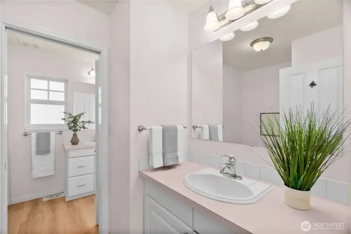 The second sink in the primary bath is housed with the commode and can do double duty as a powder room when the pocket door is closed.