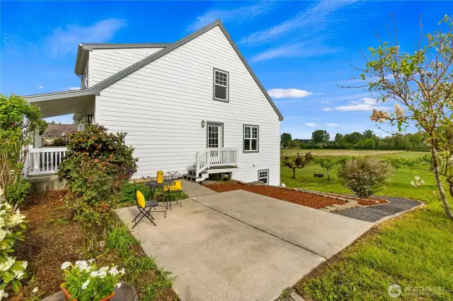 Side view of the home with a Trex deck & patio between the house and the barn. A gravel pathway leads to the lower level of the home & terraced garden beds along the path provide great gardening opportunities!