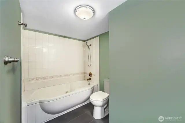 Jacuzzi tub with shower wand and tile surround   Mirrored medicine cabinet / Tile floors
