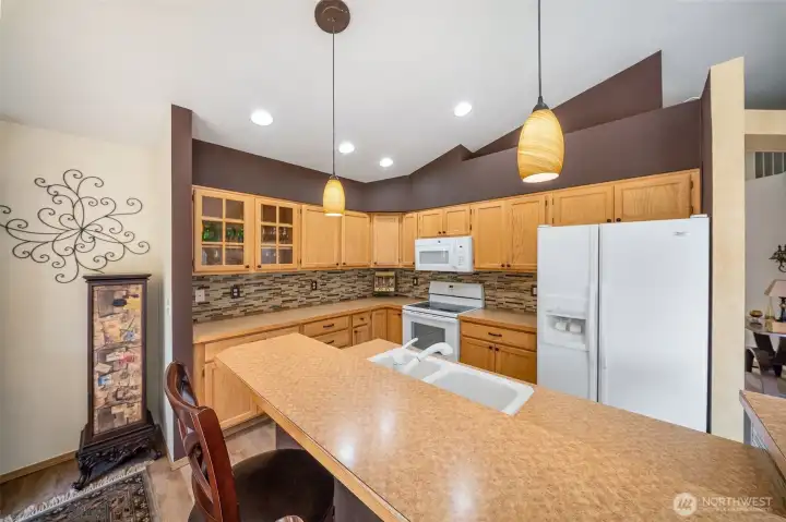 Kitchen features lighted glass display cabinets and full height tile backsplask