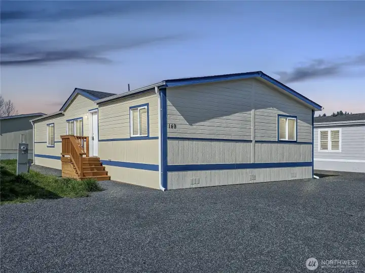 Virtually staged evening view of the exterior showing the home in a warm twilight setting.