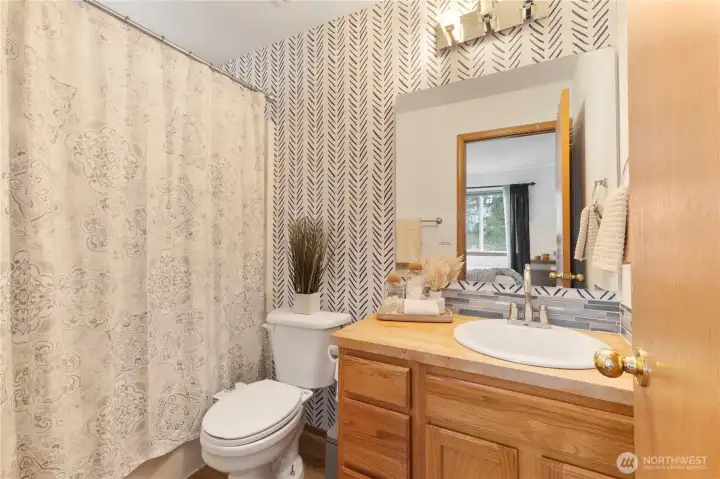 The full bath off the primary is nicely refreshed with laminate flooring, wood countertop & tile backsplash