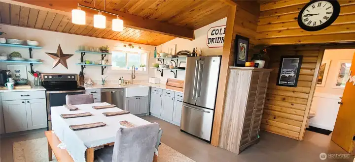 A bright and welcoming kitchen where coastal charm meets functionality, featuring quartz counter tops, a farmhouse sink, cozy dining, SS appliances and stunning ocean views for the perfect gathering spot.