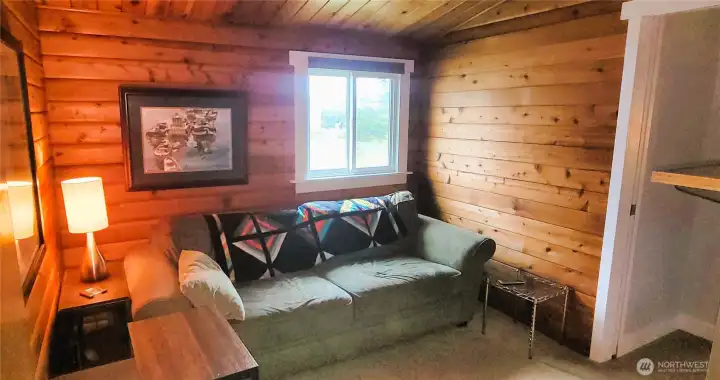 A tranquil private sitting room offering a cozy retreat, seamlessly leading into the expansive primary suite. Warm wood tones and thoughtful design create an inviting space for relaxation and quiet moments.