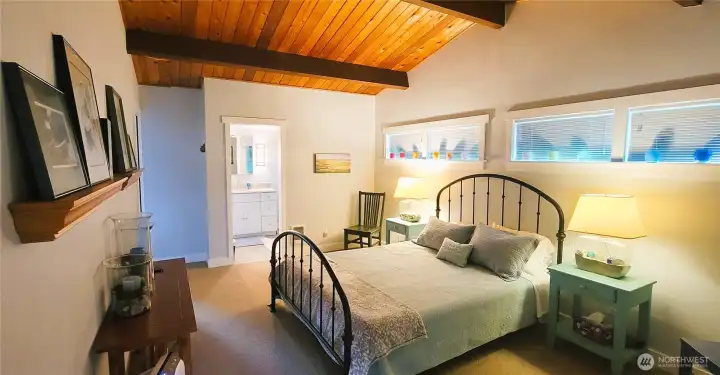 A refined primary suite showcasing the seamless flow into the elegant ensuite bathroom, where warm wood tones, sophisticated finishes, and thoughtful design create a tranquil retreat.