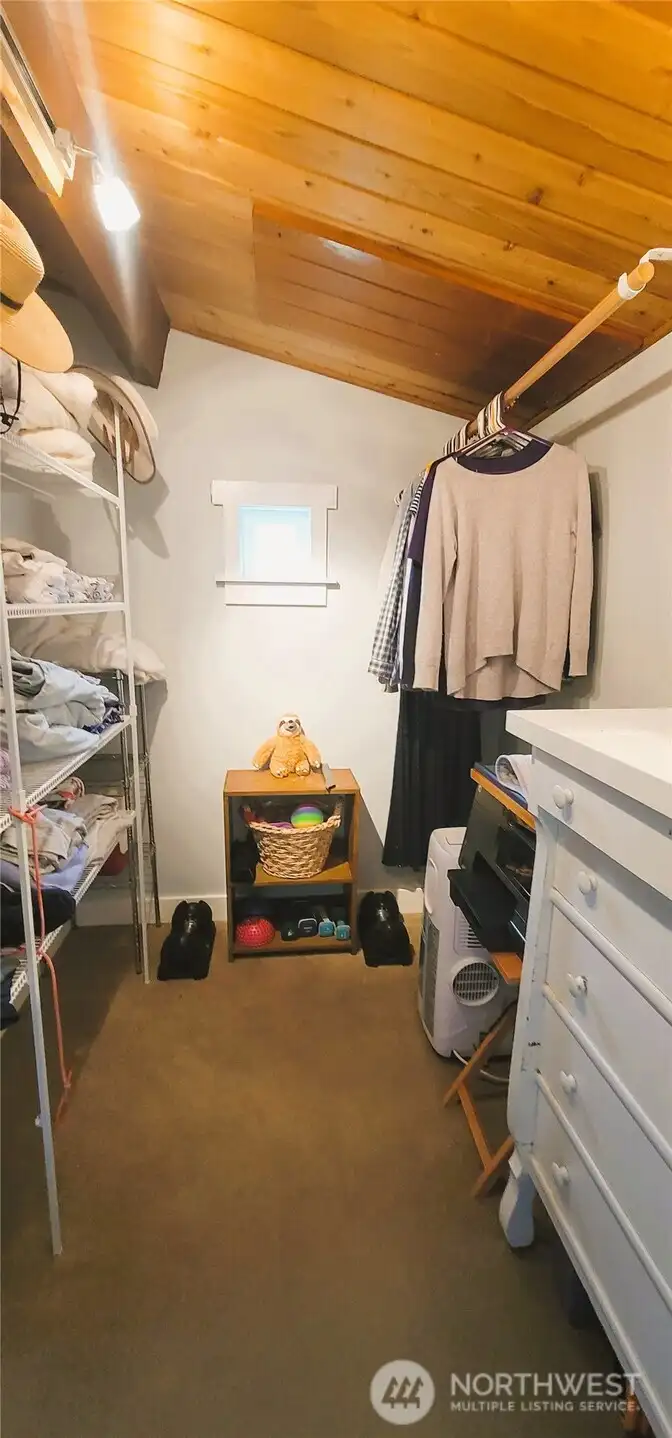 A well-appointed walk-in closet featuring ample storage and a thoughtfully placed small window, allowing natural light to brighten the space while maintaining privacy and functionality.