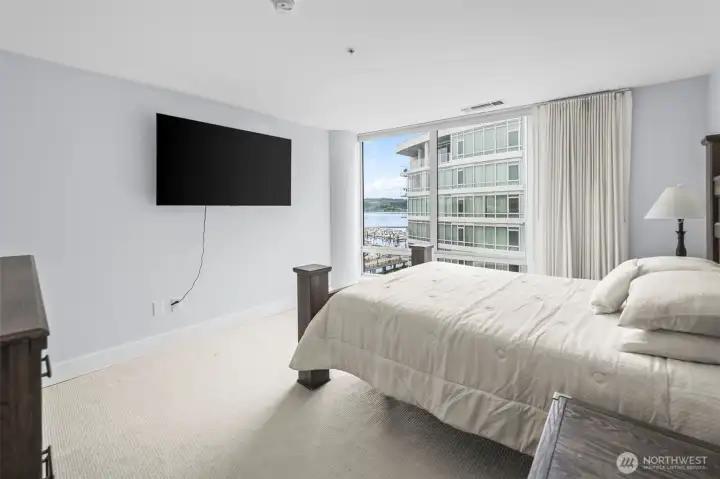 Primary with floor to ceiling windows viewing the courtyard and water.
