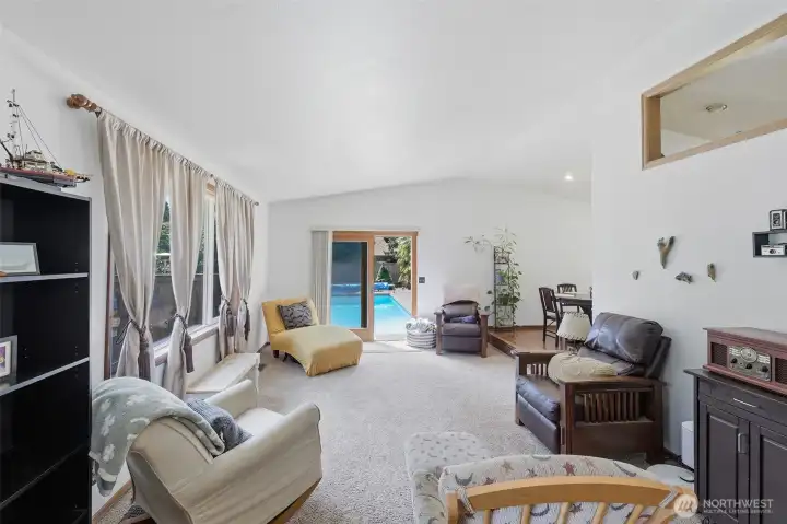 Living room with vaulted ceilings and door to inground swimming pool. Living room with vaulted ceilings and door to inground swimming pool.