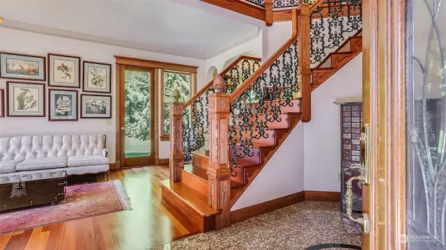 The beautifully detailed wood staircase, adorned with intricate wrought-iron balusters, sets the tone for the exquisite design found throughout the home.