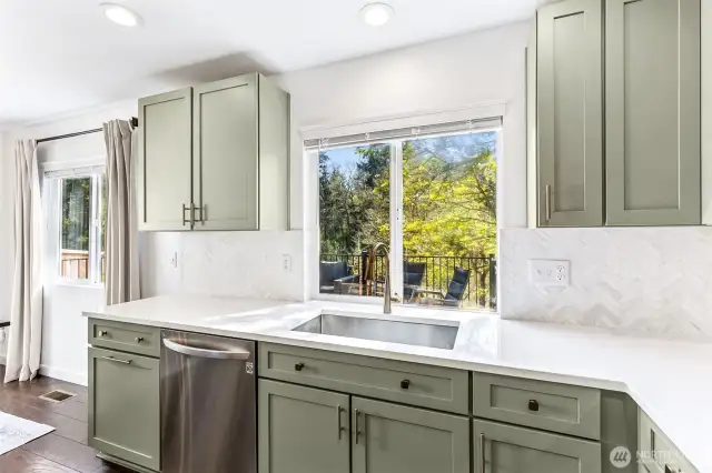 Herringbone tile backsplash contrasts the sparkling white quartz counters.  Functional deep sink and updated lighting. Newer appliances.