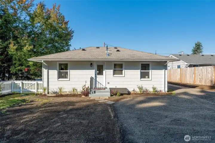 Rear view of the house. Crawl space access to the right of the stairs. New vapor barrier installed and vent covers in the crawl space. New grass seed planted.